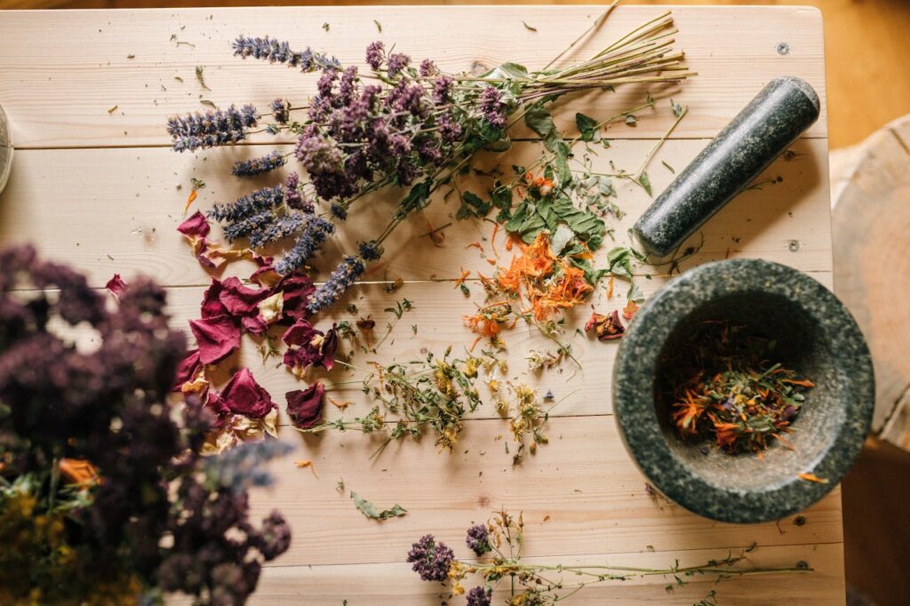 pexels-photo-5480238 Flat lay of dried herbs and flowers with a stone mortar and pestle on a rustic wooden table.