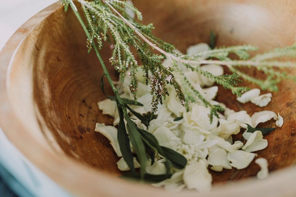 pexels-photo-6724381 Wooden bowl filled with fresh herbs and flowers for aromatherapy and relaxation.